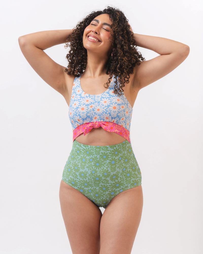 Photo of a woman wearing a blue and green floral knotted one piece swim suit