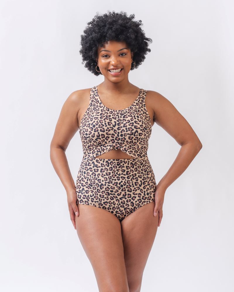 Photo of a woman with her hands on her hips wearing a leopard print one piece swimsuit