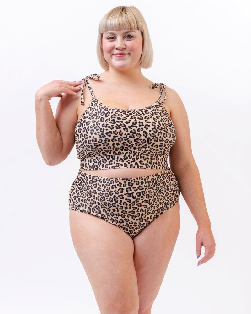 Photo of a woman wearing a leopard print shoulder-tie swim crop top and a leopard print high waist swim bottom