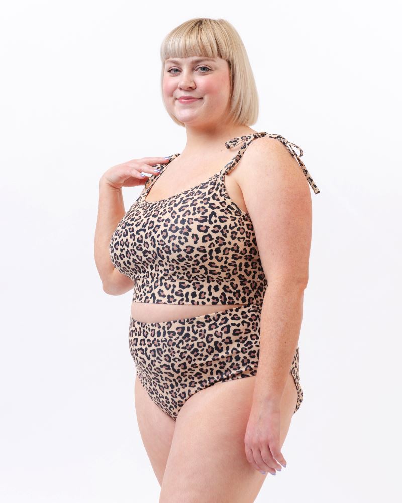 Photo of a woman from the side wearing a leopard print cropped swim top with leopard print high waist swim bottoms