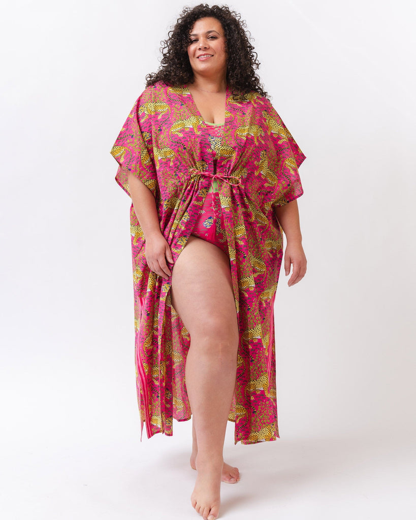 Photo of a woman wearing a bold pink print featuring tigers swim suit cover-up and a bold pink and green print featuring tigers one-piece swim suit