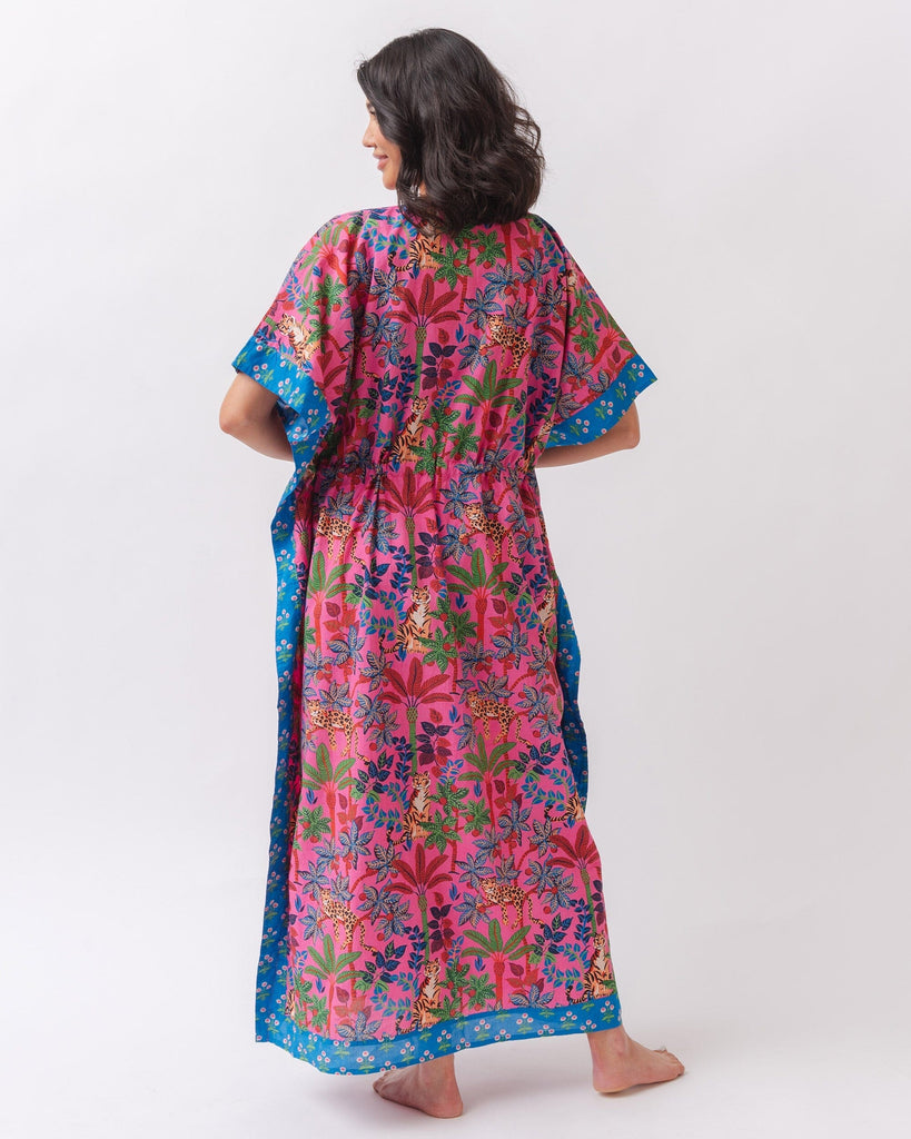 Photo of a woman wearing a bold pink and blue print featuring tigers and leopards caftan swim suit cover-up- back angle