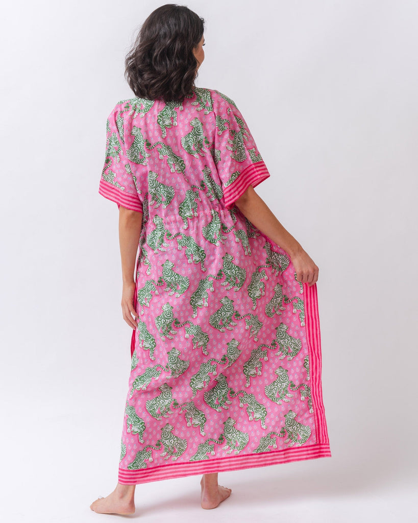 Photo of a woman with her back facing us wearing a bold pink and green tiger print long cover up