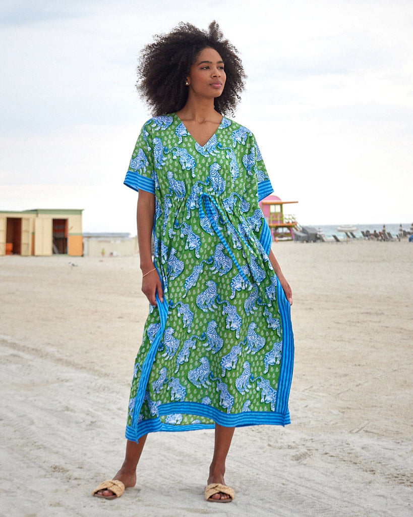 Photo of a woman at the beach wearing a bold green tiger print long cover up
