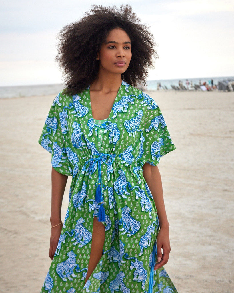 Photo of a woman at the beach wearing a bold green tiger print long cover up with a bold green and pink tiger print swim one piece underneath