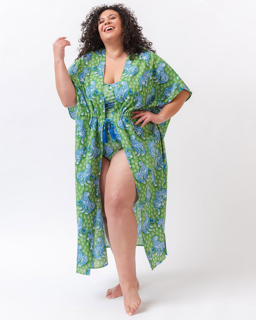 Photo of a woman wearing a bold green tiger print long cover up with a bold green and pink tiger print swim one piece underneath