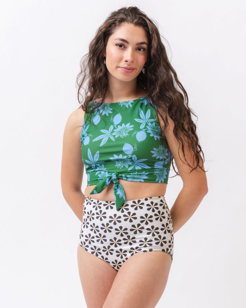 Photo of a woman wearing a green and blue floral swim crop top and a black and white floral swim bottom