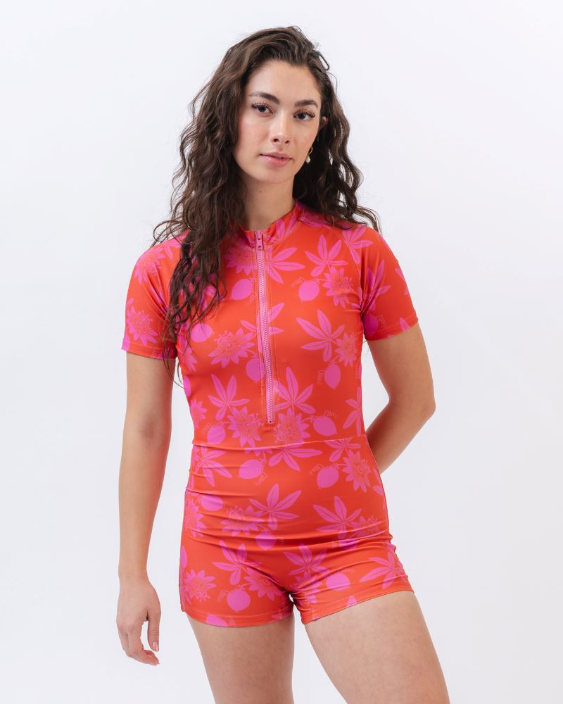 Photo of a woman wearing a red and pink floral rash guard one-piece swimsuit