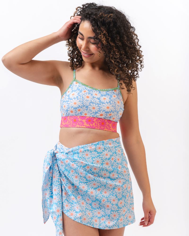 Photo of a woman wearing a blue and pink floral cropped swim top with a blue floral sarong tied at her waist