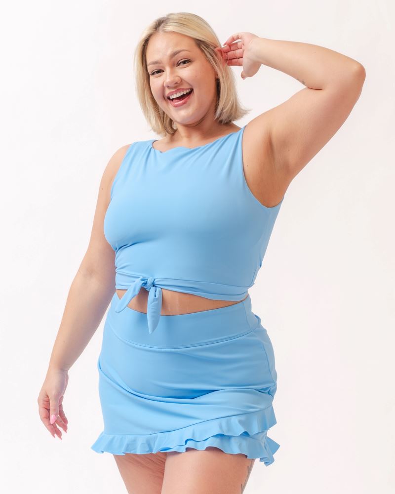 Photo of a woman wearing a light periwinkle blue cropped swim top with a light periwinkle blue swim skirt