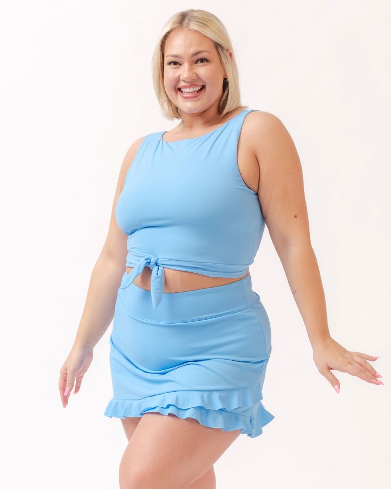 Photo of a woman wearing a light periwinkle blue cropped swim top with a light periwinkle blue swim skirt