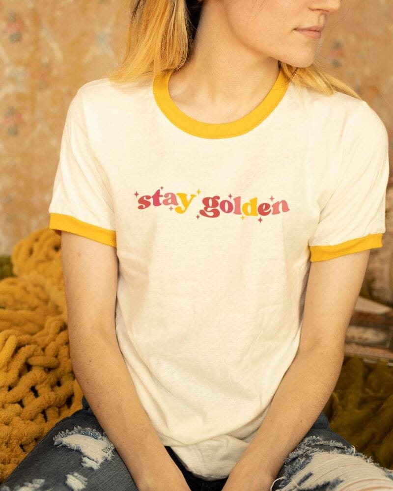 Photo of woman wearing a white t-shirt that says "Stay Golden"