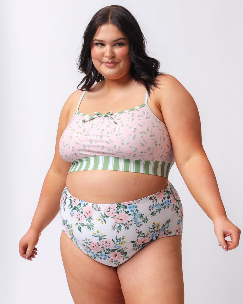 Photo of a woman wearing a pink floral cropped swim top with pink and white floral high waist swim bottoms