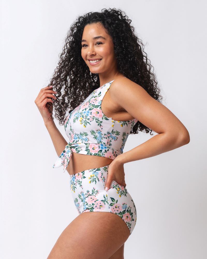 Photo of a woman from the side wearing a pink and white floral cropped swim top with pink and white floral high waist swim bottoms