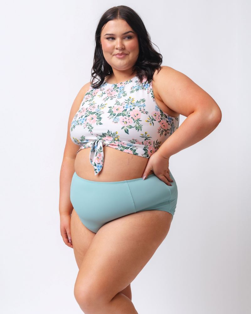 Photo of a woman wearing a light blue high waist swim bottom and a pink and white floral swim crop top