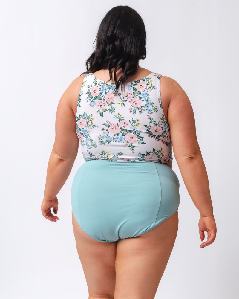Photo of a woman wearing a light blue high waist swim bottom and a pink and white floral swim crop top- back angle