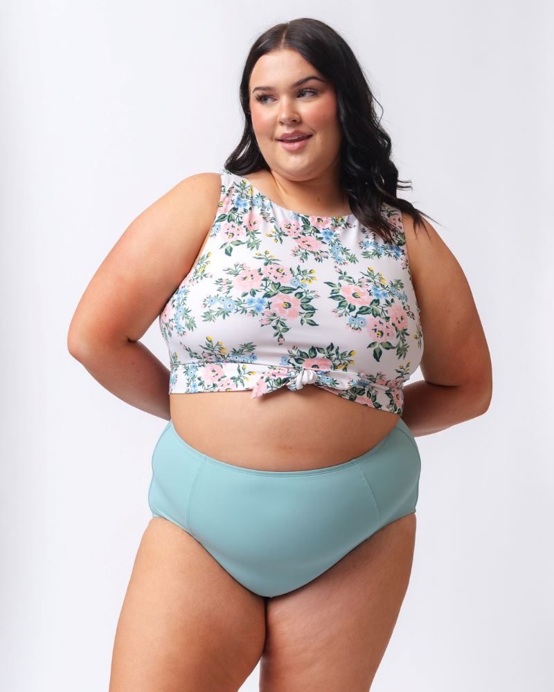 Photo of a woman wearing a pink and white floral cropped swim top with light blue high waist swim bottoms