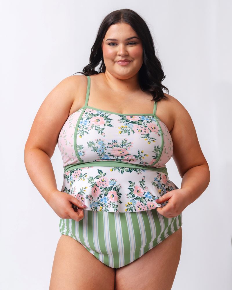 Photo of a woman wearing a pink and white floral swim top with green and white stripe high waist swim bottoms