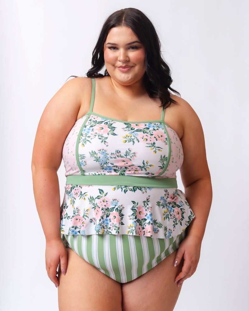 Photo of a woman wearing a pink and white floral swim top with green and white stripe high waist swim bottoms