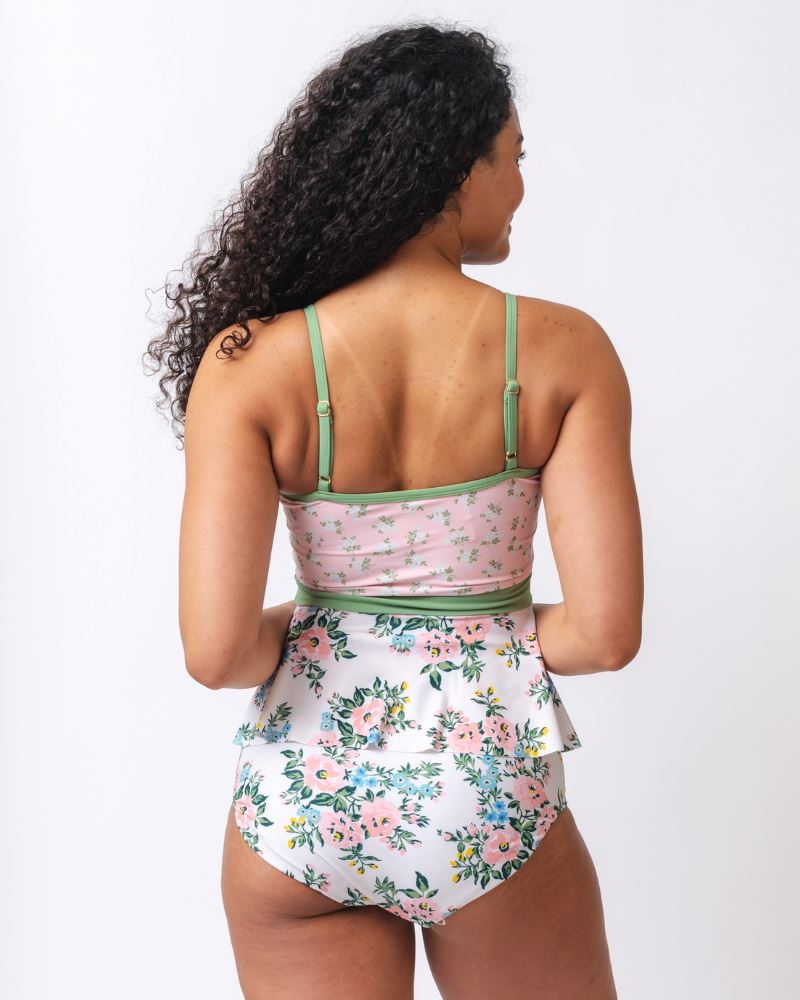 Photo of a woman with her back facing us wearing a pink and white floral swim top with pink and white floral high waist swim bottoms