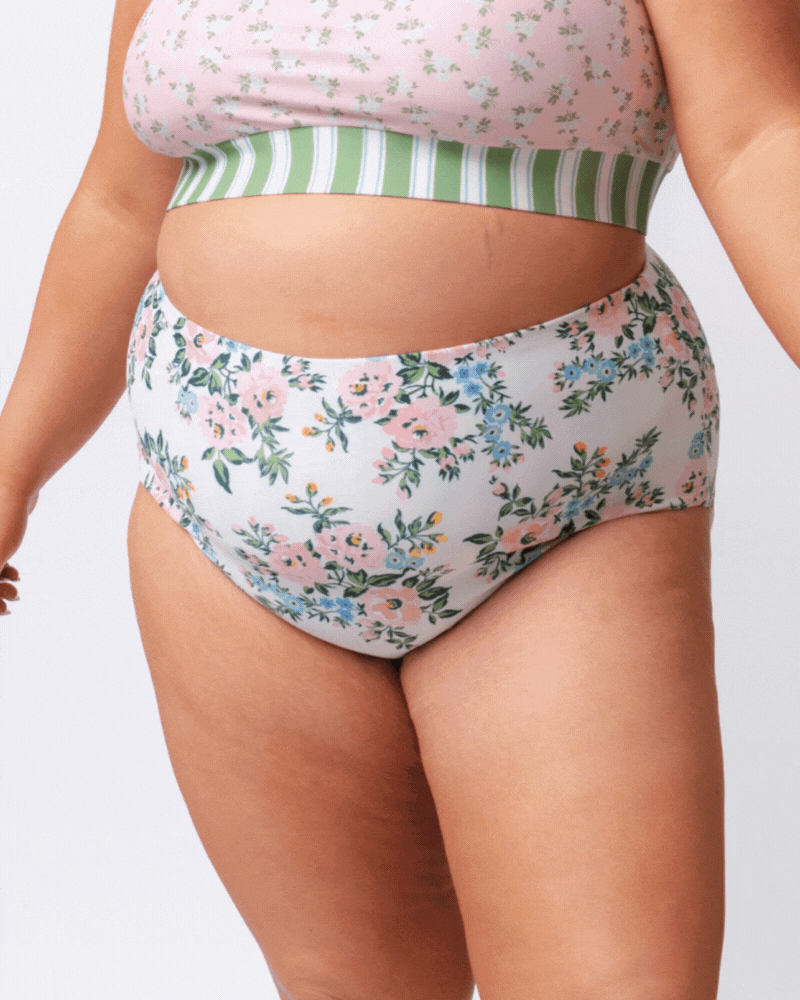 GIF of a woman wearing pink and white floral and green and white stripe high waist reversible swim bottoms