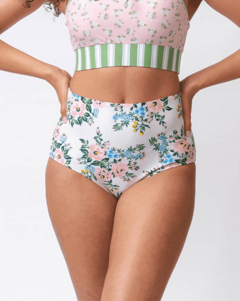 GIF of a woman wearing white and pink floral with green striped reversible high waist bottoms