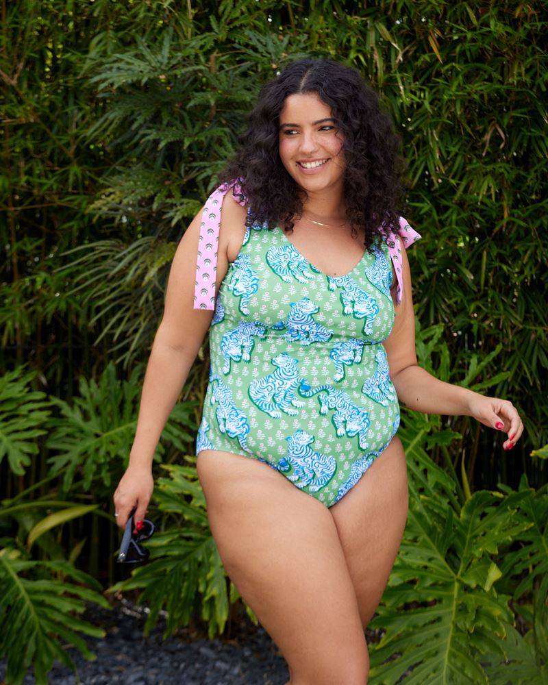 Photo of a woman wearing a bold green and pink tiger print shoulder tie swim one piece