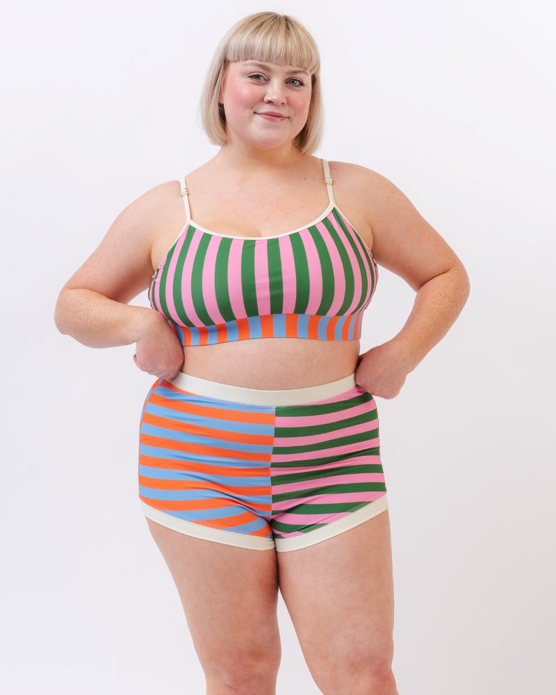 Photo of a woman wearing a multi-colored striped swim bralette and a multi-colored striped retro swim short bottom