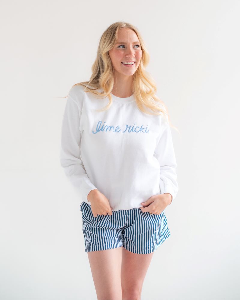 Photo of woman wearing a Lime Ricki white crew neck sweatshirt with blue and white striped swim shorts