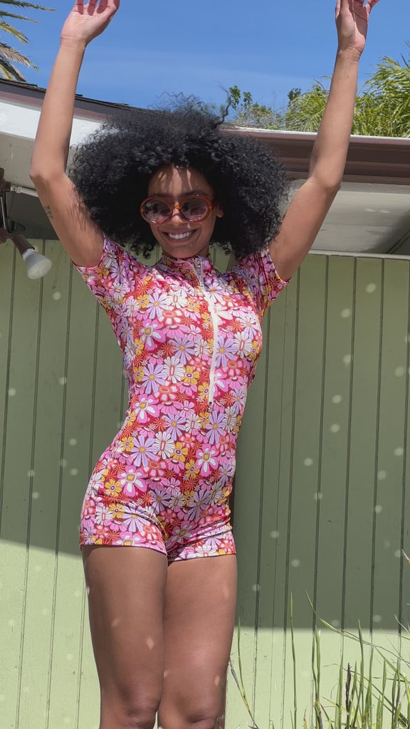 Video of a woman wearing a groovy Blooms floral rash guard one-piece swim suit