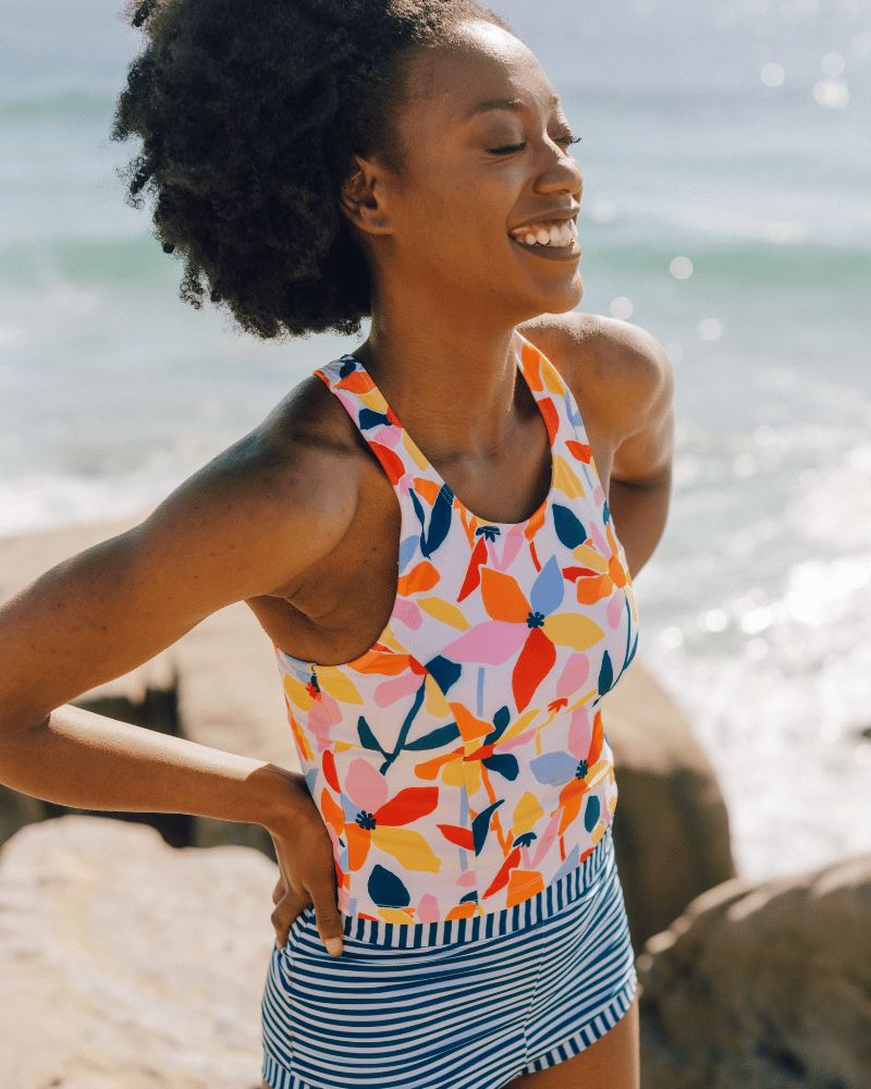 Photo of a woman wearing a June floral swim racer-back swim crop top and an Indigo stripe swim short bottom side angle