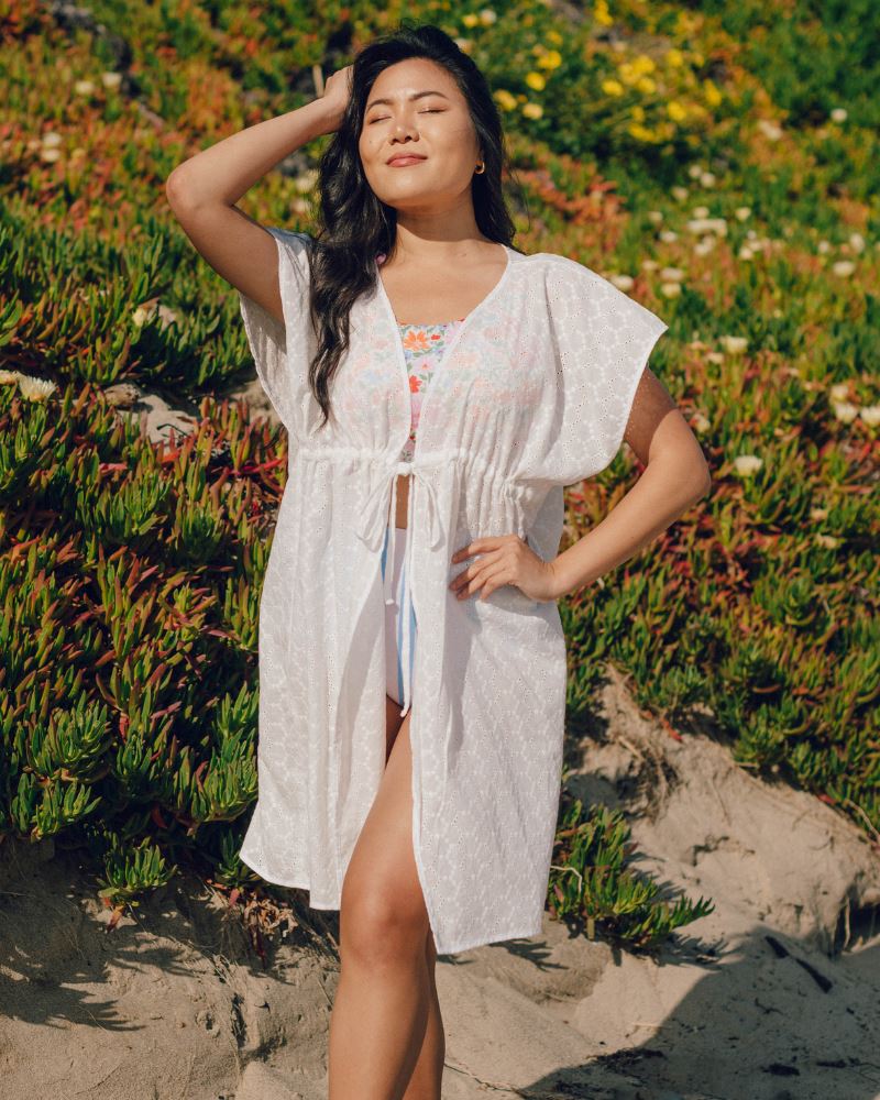 Photo of a woman wearing a white kaftan Cover-up and a floral swim crop top