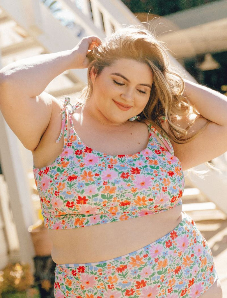 Photo of a woman wearing a floral shoulder-tie swim crop top and a floral swim bottoom