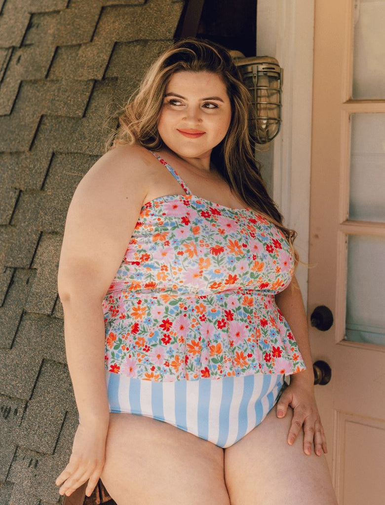 Photo of a woman wearing a floral peplum swim top and a blue and white stripe swim bottom