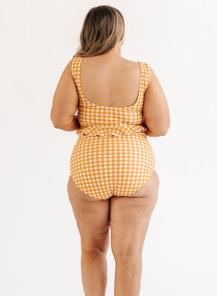 Photo of woman wearing yellow and white gingham swim top with yellow and white gingham swim bottoms back angle