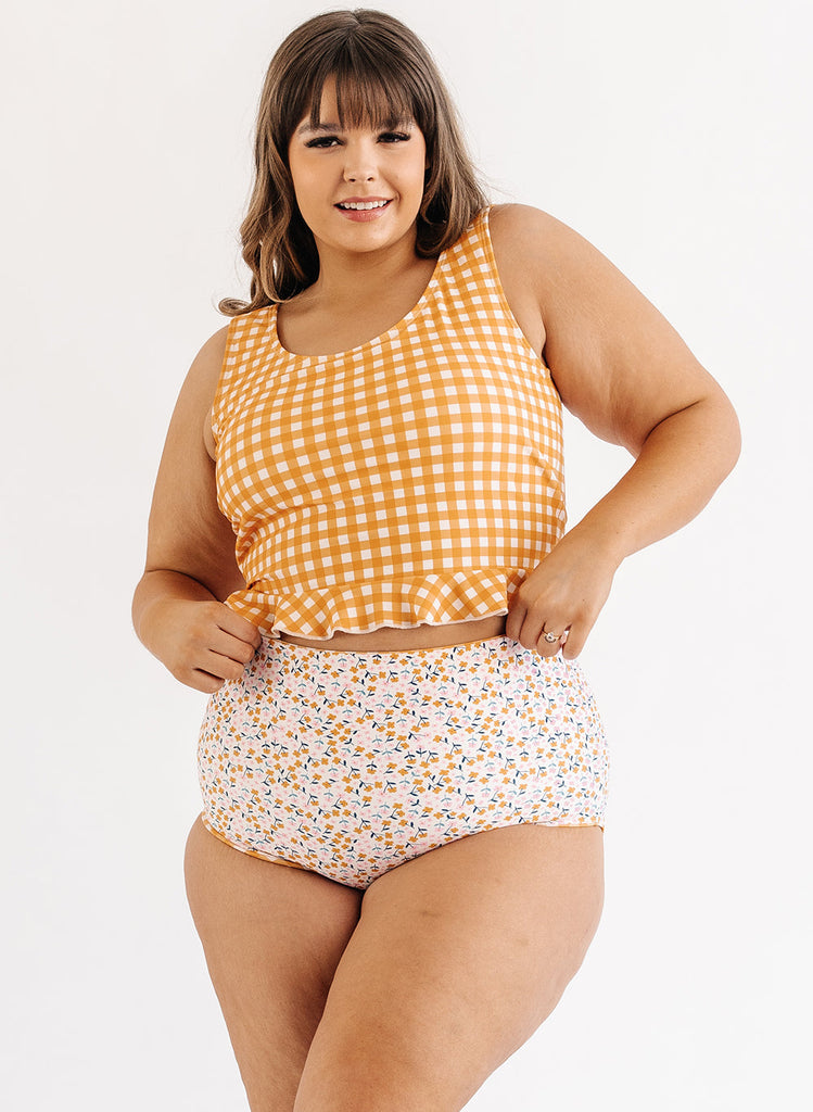 Photo of woman wearing yellow and white gingham swim top with multi color floral swim bottoms