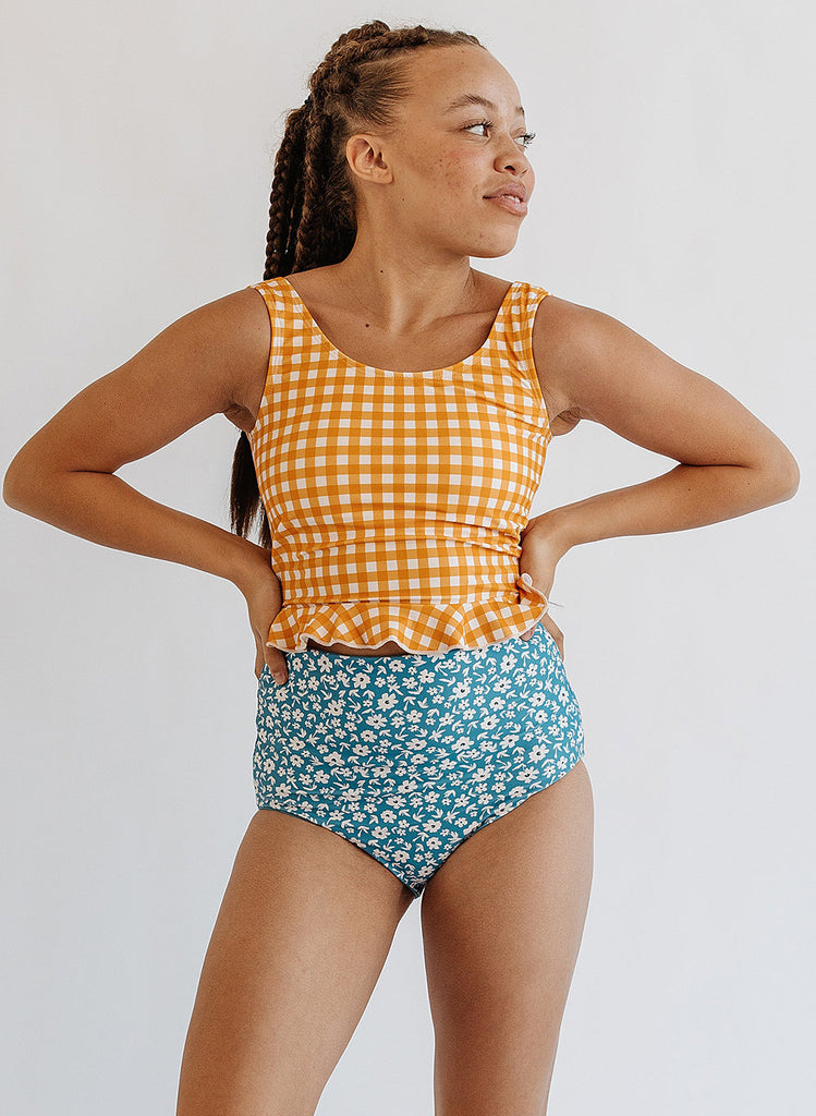 Photo of woman wearing yellow and white gingham swim top with blue floral swim bottoms
