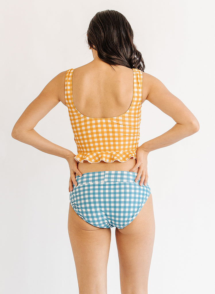 Photo of woman wearing yellow and white gingham swim top with blue and white gingham swim bottoms back angle