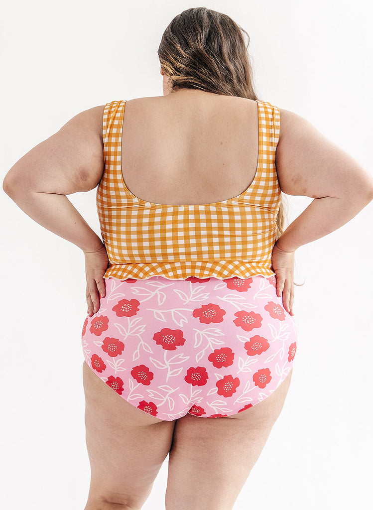 Photo of woman wearing yellow and white gingham swim top with pink floral swim bottoms back angle