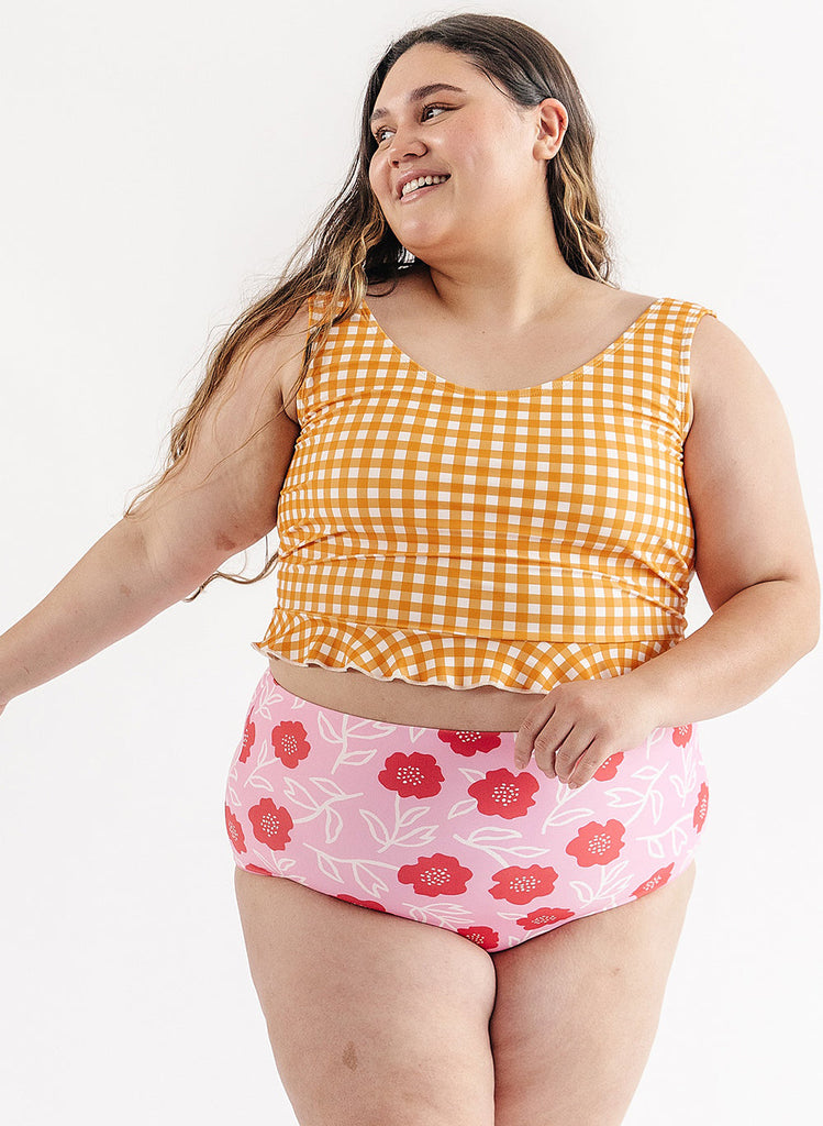 Photo of woman wearing yellow and white gingham swim top with pink floral swim bottoms