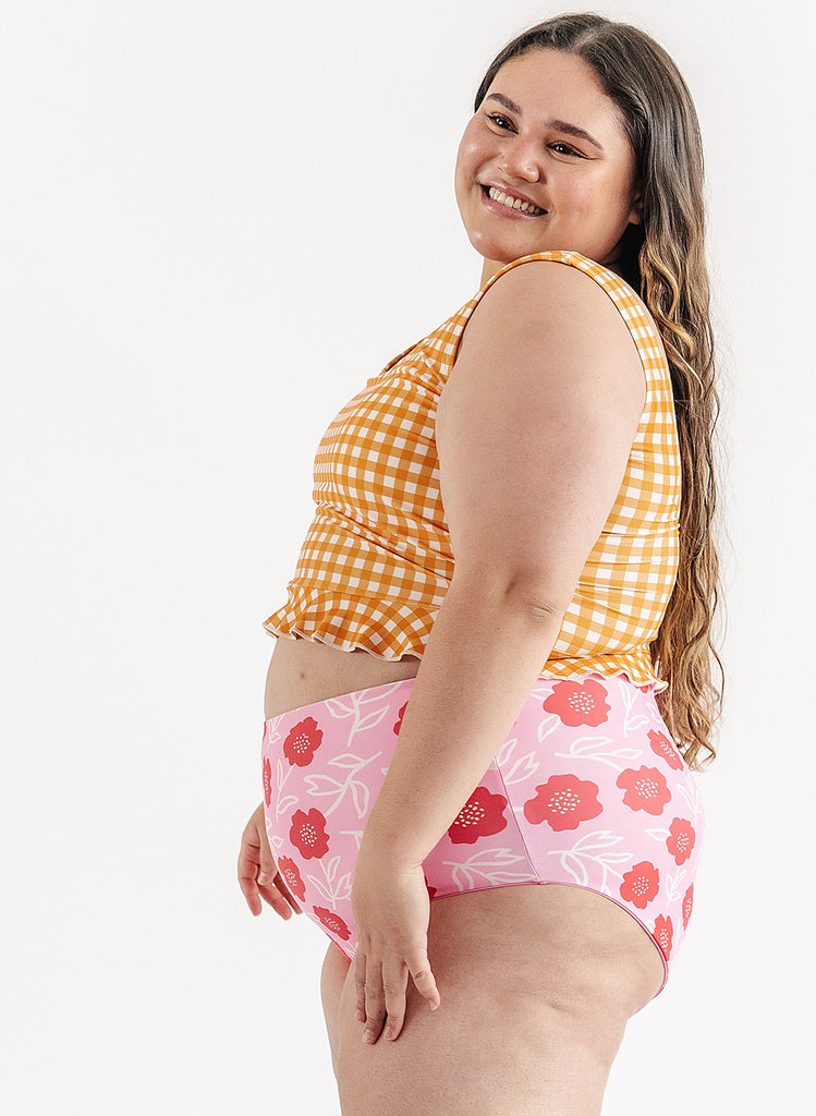Photo of woman wearing yellow and white gingham swim top with pink floral swim bottoms side angle