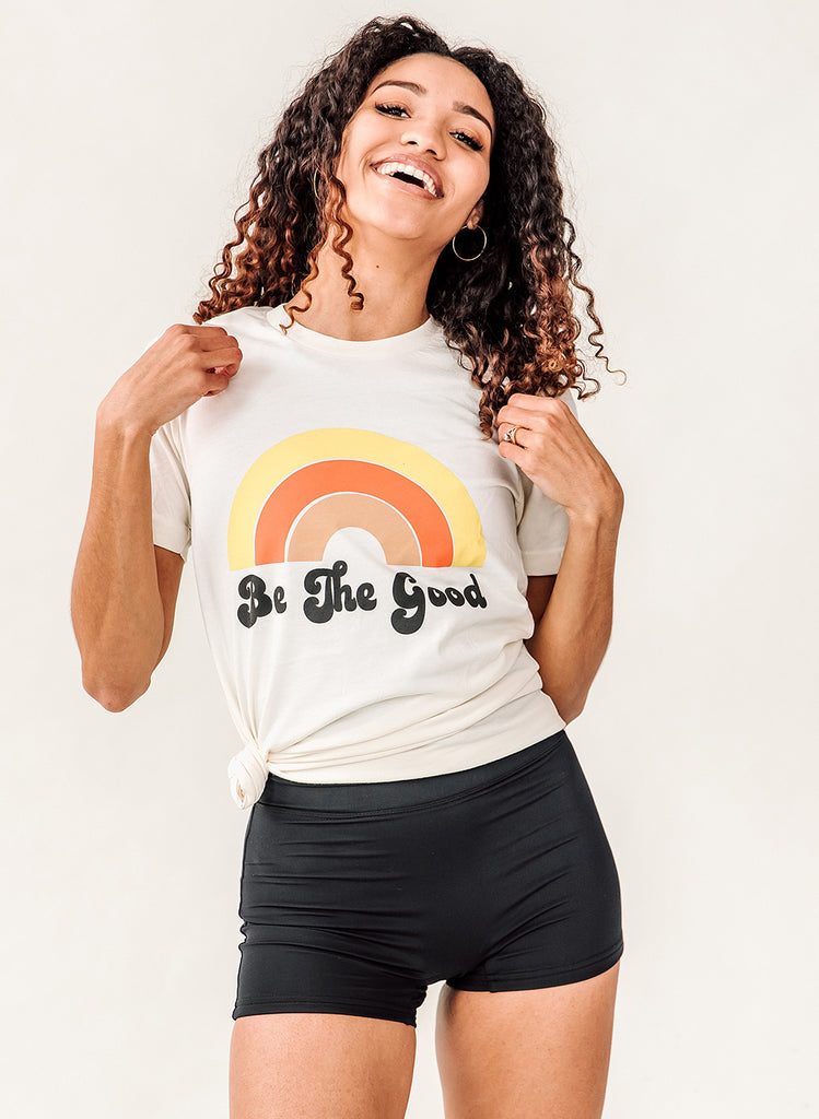 Photo of woman wearing white "Be The Good" t-shirt with black high waist swim bottoms