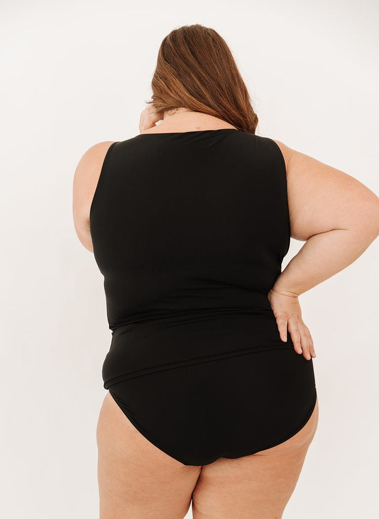 Photo of a woman in a black boat neck swim top and black swim bottoms from the back