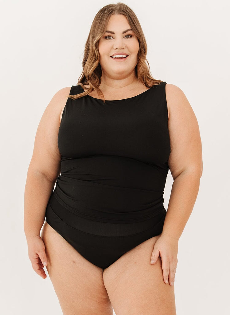 Photo of a woman in a black boat neck swim top and black swim bottoms