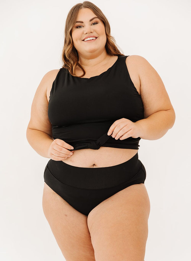 Photo of a woman in black classic swim bottoms and black knotted swim crop top