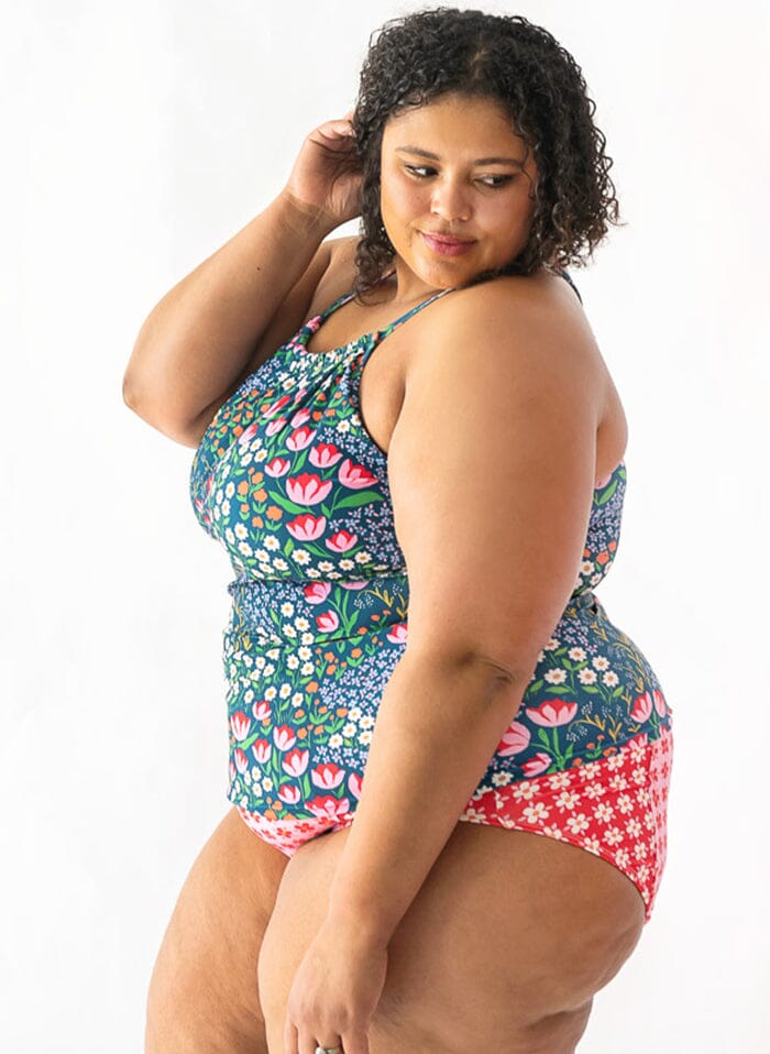 Photo of a woman wearing a Blixen double-cinch swim top and a red and white floral swim bottom side angle