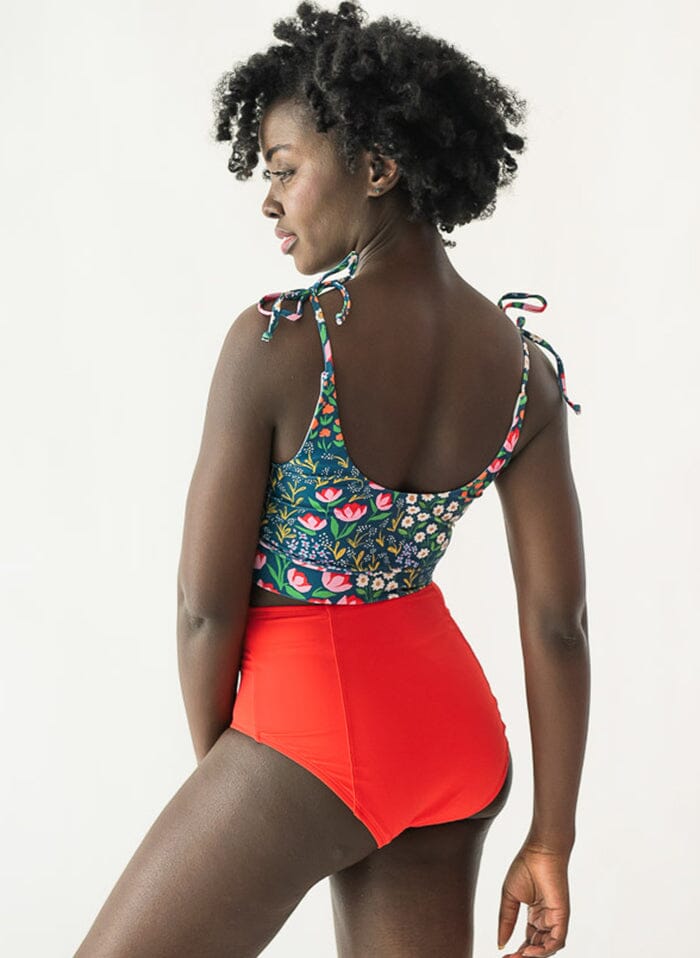 Photo of a woman wearing a Blixen shoulder-tie swim crop top and a red swim bottom back angle