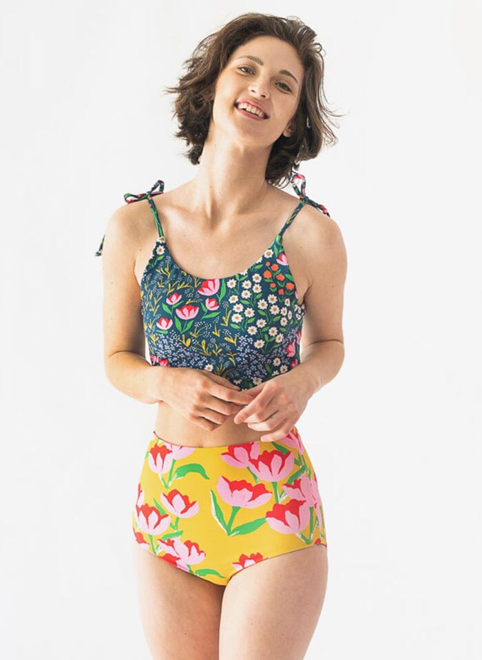 Photo of a woman wearing a Blixen shoulder-tie swim crop top and a yellow floral swim bottom