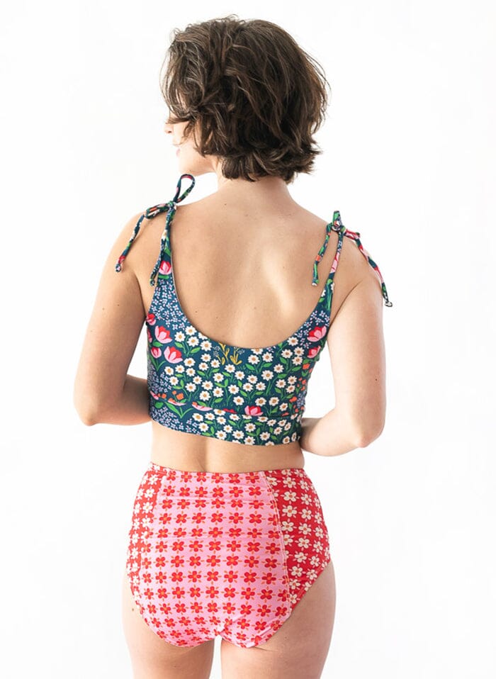 Photo of a woman wearing a pink Margrethe swim bottom and a Blixen shoulder-tie swim crop top back angle