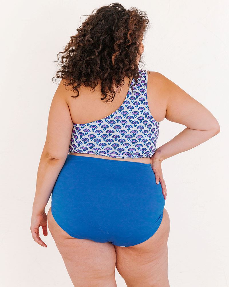 Photo of a woman wearing a Block Floral One-shoulder swim crop top and a blue swim bottom back angle